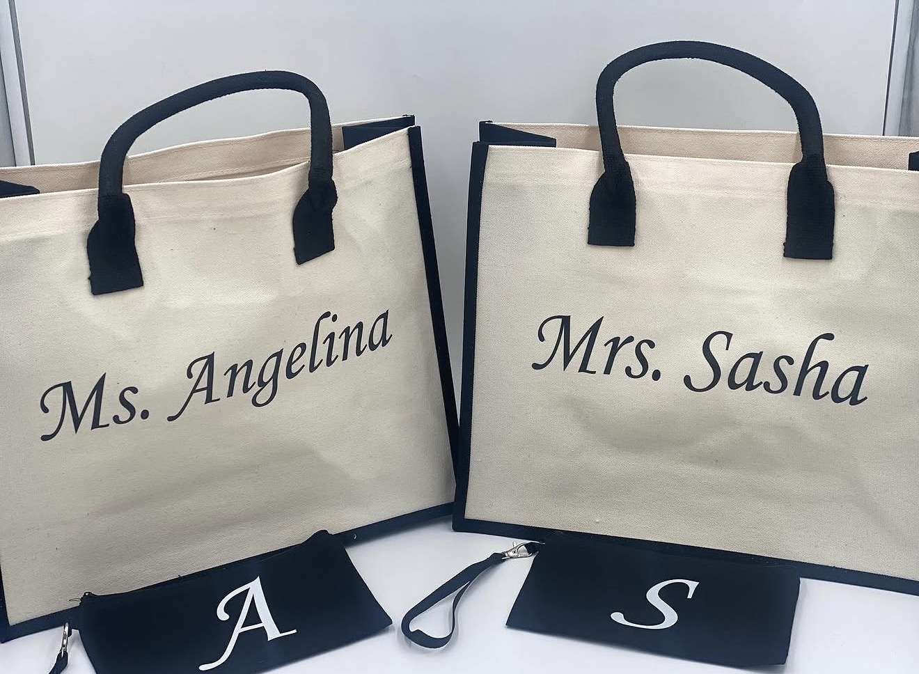 Cream tote bags personalized with Ms. Angelina and Mrs. Sasha, with matching initial wristlets