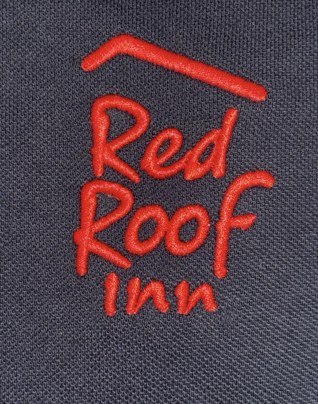 Close-up of red Red Roof Inn logo embroidery on dark textured fabric